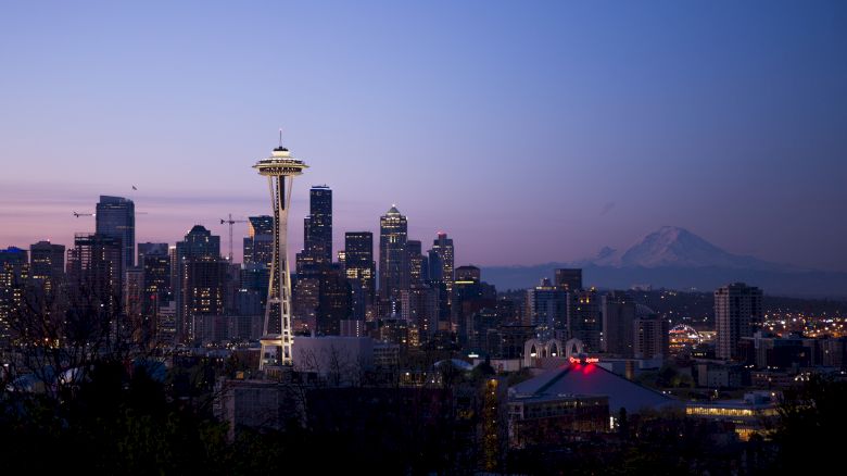 The image features the Seattle skyline at dusk, showcasing the Space Needle and Mount Rainier in the background.